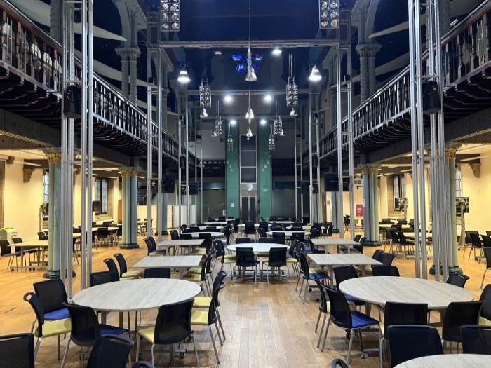 Flat floored hall with tables and chairs in groups.