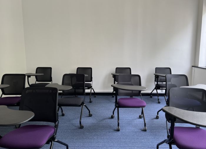 Flat floored teaching room with tablet chairs.