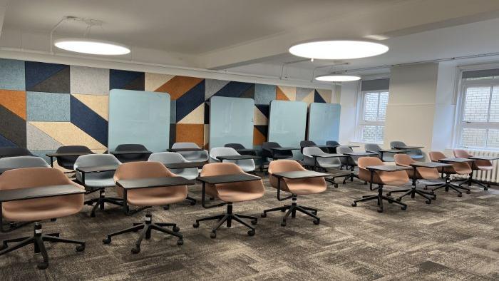 Flat floored teaching room with rows of tablet chairs, and moveable glassboards.