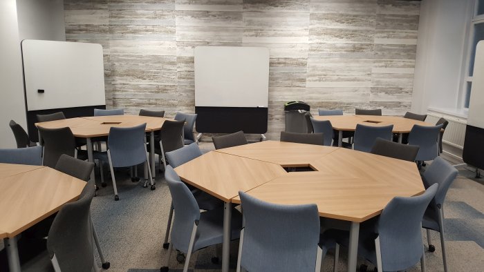 Flat floored teaching room with groups of tables and chairs and movable whiteboards