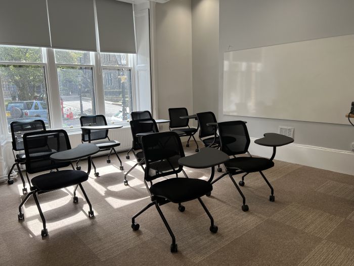 Flat floored teaching room with tablet chairs and whiteboard.