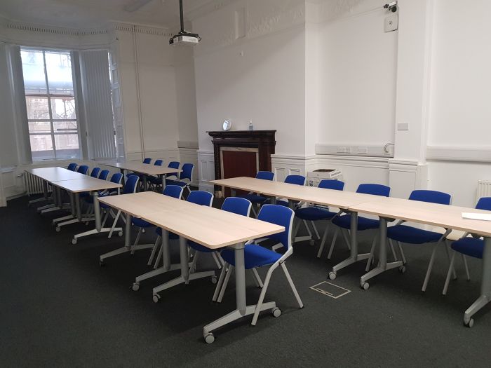 Flat floored teaching room with rows of tables and chairs