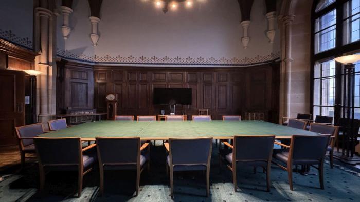 Flat floored meeting room with boardroom table and chairs, and video monitor.