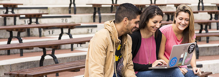 Students using laptop on benches