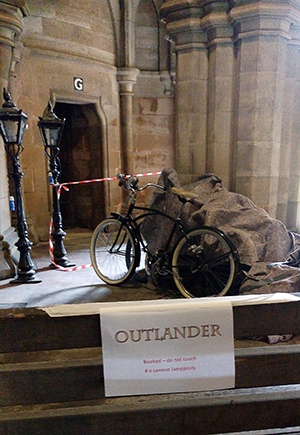 An old-fashioned bicycle and two lampposts for set-dressing, stored in the cloisters