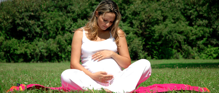 Photo of pregnant woman sitting on grass