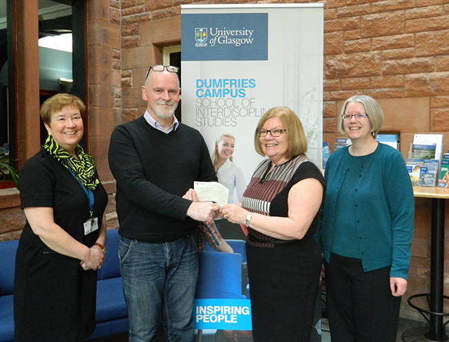 University of Glasgow colleagues Audrey Clowe (left) and Natalie Anderson (right) who organised the University of Glasgow’s Christmas Concert joined Dr Carol Hill, Head of School at the University of Glasgow in Dumfries to present Owen Fielding, Business Operations Manager from Compass Brain Injury Specialists with a cheque for £864.02. 