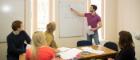 A class of students looking a whiteboard where a tutor is writing 