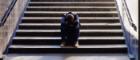 Image of a youngster with head bowed sitting forlornly on an underpass staircase.