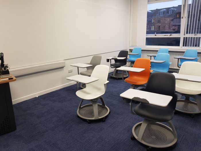 Flat floored teaching room with tablet chairs.