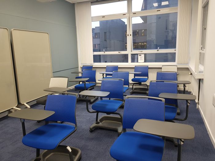 Flat floored teaching room with tablet chairs and movable glassboards.