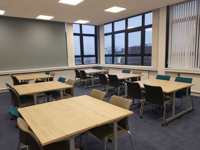 Flat floored teaching room with tables and chairs.