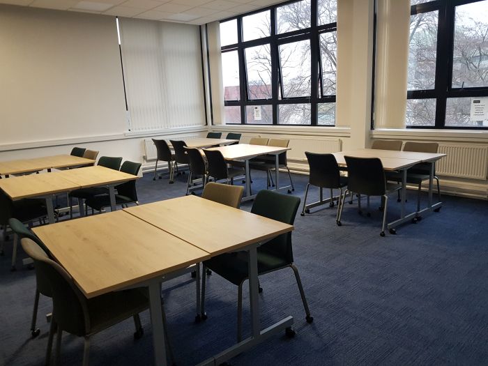 Flat floored teaching room with tables and chairs.