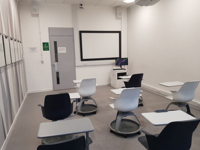 Flat floored teaching room with tables and chairs in groups