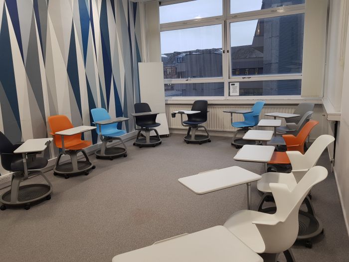 Flat floored teaching room with tablet chairs and moveable whiteboards.