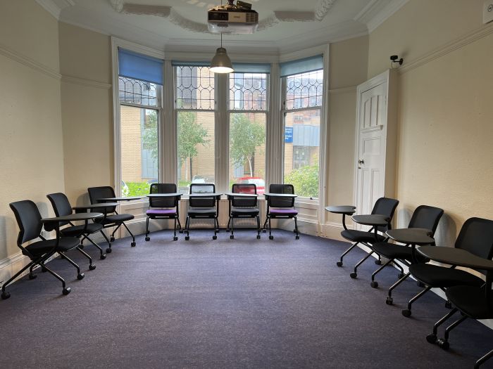 Flat floored teaching room with tablet chairs and projector.