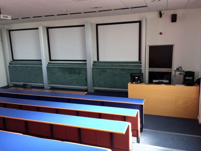 Raked lecture theatre with fixed seating, screens, chalkboards, visualiser and PC