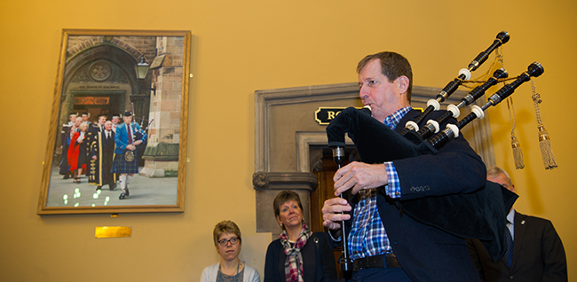 Image of Alastair Campbell playing the pipes at the unveiling of a portrait of his late brother Donald