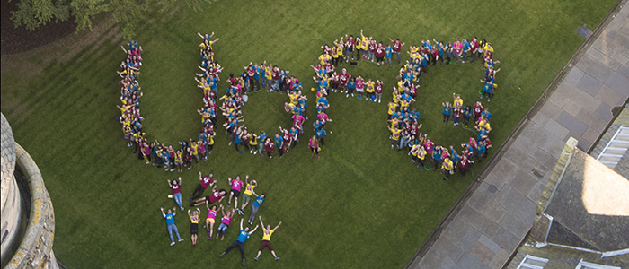 Image of students - taken from height - lying on the quads spelling the words UofG