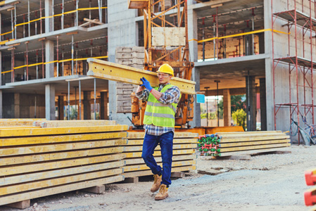 Construction worker carrying planks