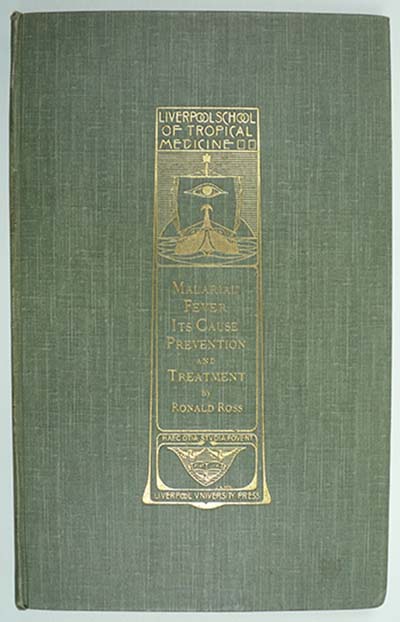 photograph of a green hard back book cover decorated with gold leaf.  The Decoration is the title and author written out in Art Deco style writing and includes an image depicting the brow of a ship approaching through water with its sail raised.  The sail has an eye motif as decoration.