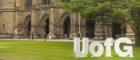 A student with the UofG sign in a quadrangle during graduation