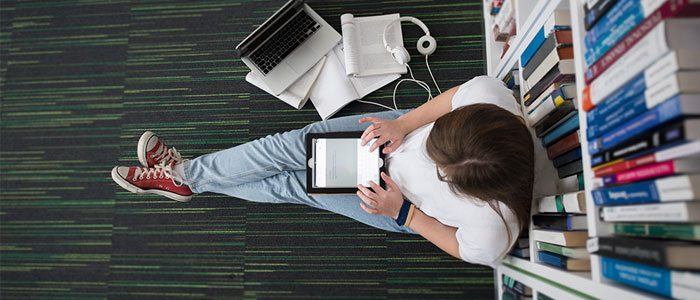 Image of a postgraduate student using a tablet in library