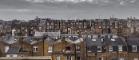 Rooftop view of old houses in London with grey sky and clouds. 700 pixels