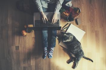Photo of man working from home with laptop and cat