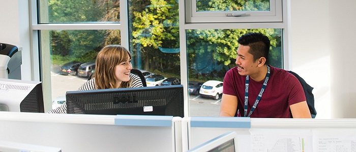 Image of male and female sitting at a desk in a Stoker building office