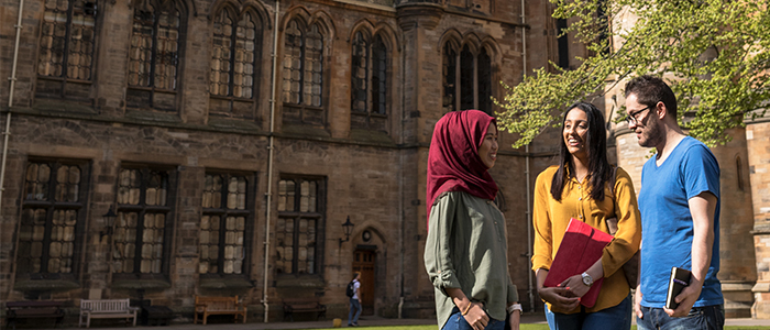 three students standing in the quad