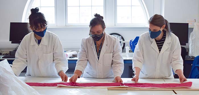 Three students examining some fabric