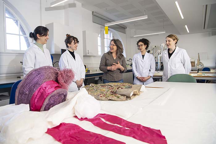 Students and lecturer gathered around fabric on table