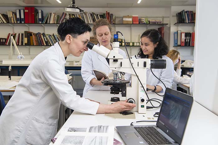 A Textile Conservation student inspects a sample using a microscope