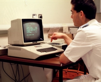 Nurse at an older PC demonstrating the computerised record system anaesthestics 1948 -2010.