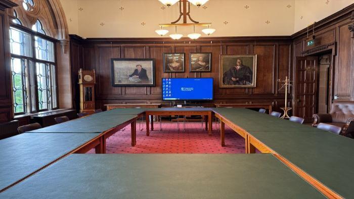 Flat floored meeting room with boardroom table and chairs, and video monitor.
