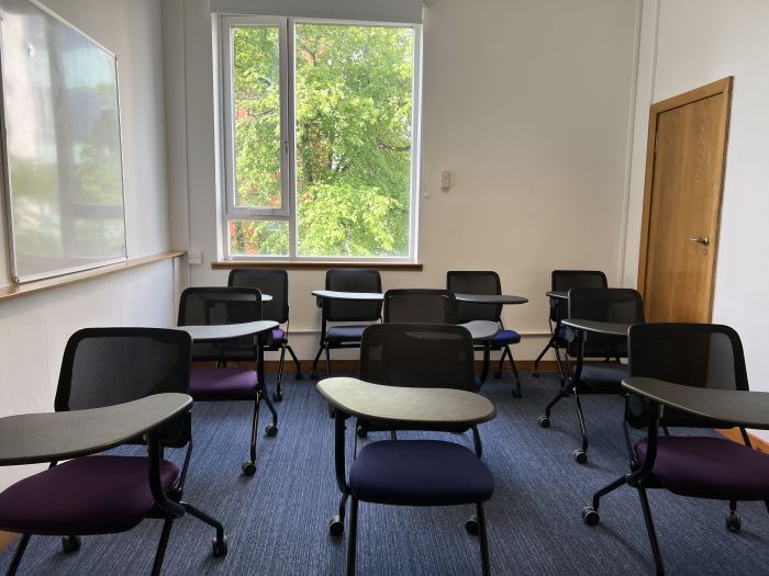 Flat floored teaching room with tablet chairs and whiteboard.