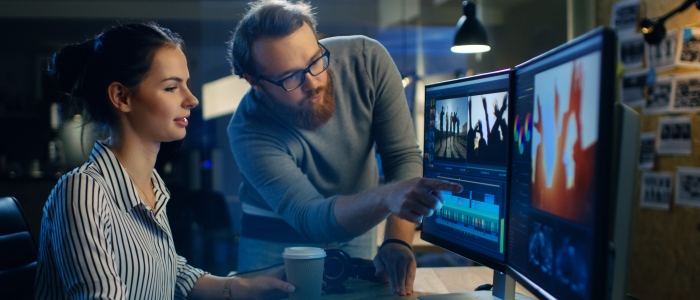 Two students reviewing a film editing suite on a computer