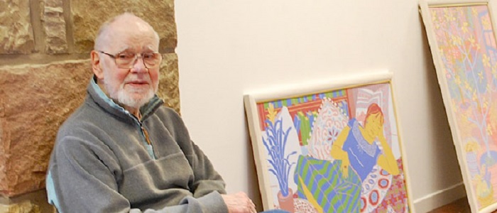 A photo of the artist Norman Gilbert in his studio with some of his paintings