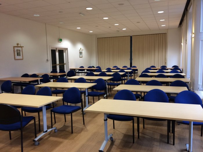 Flat floored teaching room with rows of tables and chairs