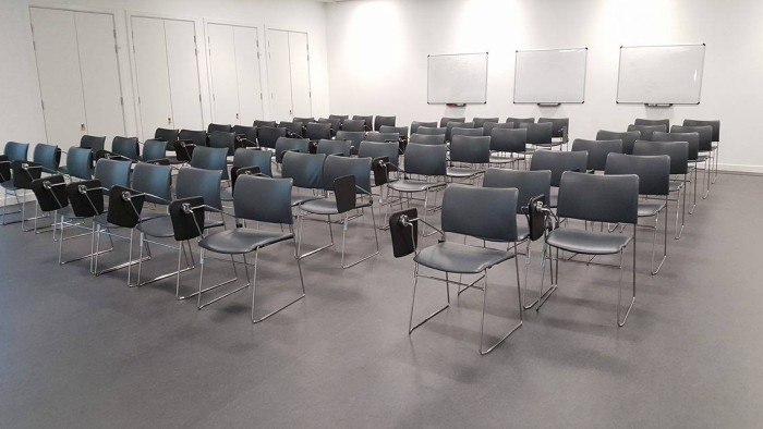 Flat floored teaching room with rows of tablet chairs and whiteboards