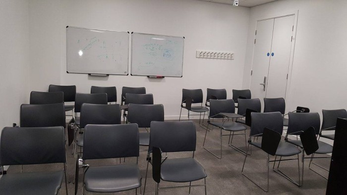 Flat floored teaching room with rows of tablet chairs and whiteboards