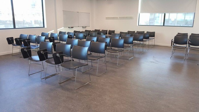 Flat floored teaching room with rows of tablet chairs and whiteboards