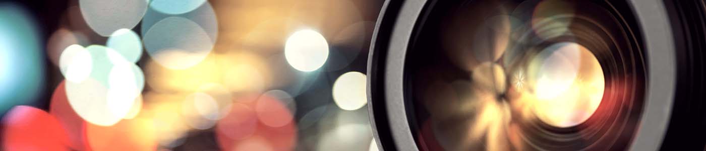 DSLR camera lens with coloured lights in background
