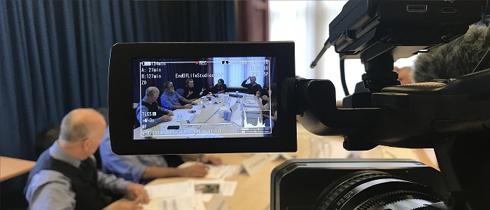 View from behind a camera, looking at a meeting