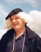 phantasy picture of Dudley Knowles, a heavyset old white man wearing a blue polo shirt and black jacket, his black flat cap covering his flowing white hair that blends in with a white cloud behind him