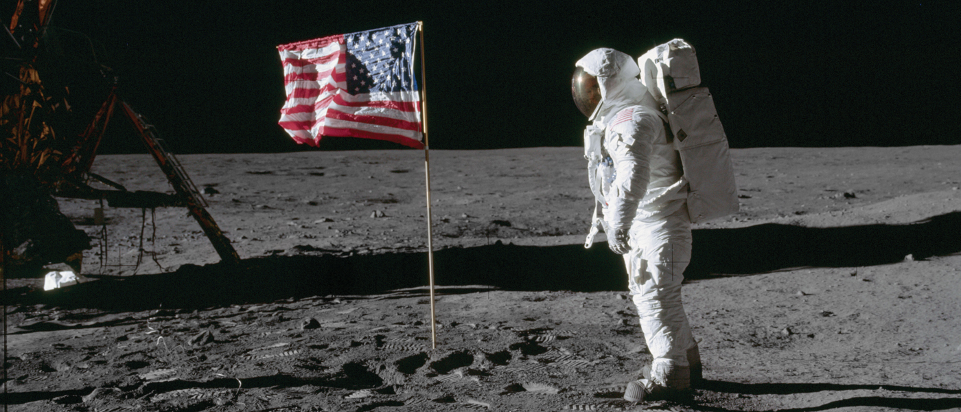 An astronaut sets foot on the moon, beside an American flag (photo: NASA).