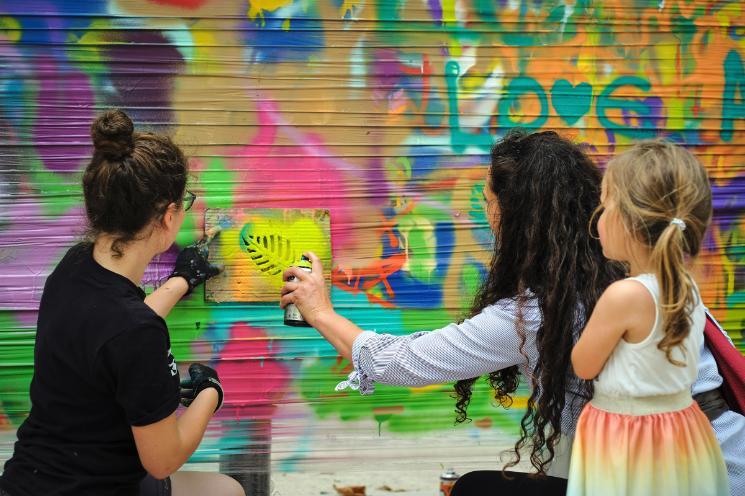 Young people creating an art work using cans of spray paint