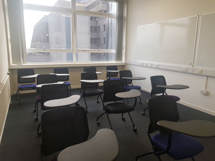 Flat floored teaching room with tablet chairs and whiteboards.