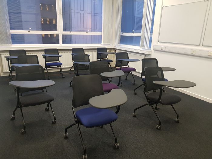 Flat floored teaching room with tablet chairs and whiteboards.